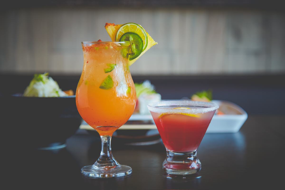 Two garnished house cocktails served on the bar.